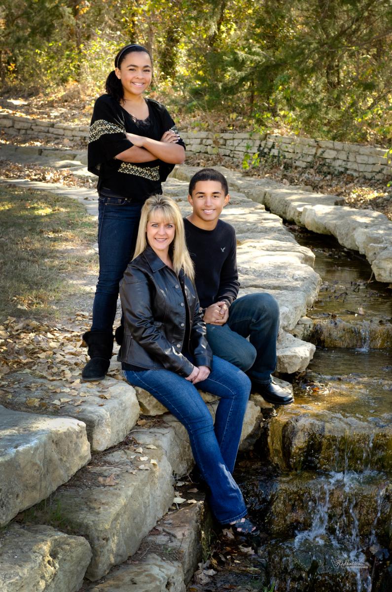 Kay Baker and her children wore black with blue jeans for this artistic landscape portrait of rocks, fallen oak leaves and stream, by Robertsons' Warehouse Photography, Wichita, KS