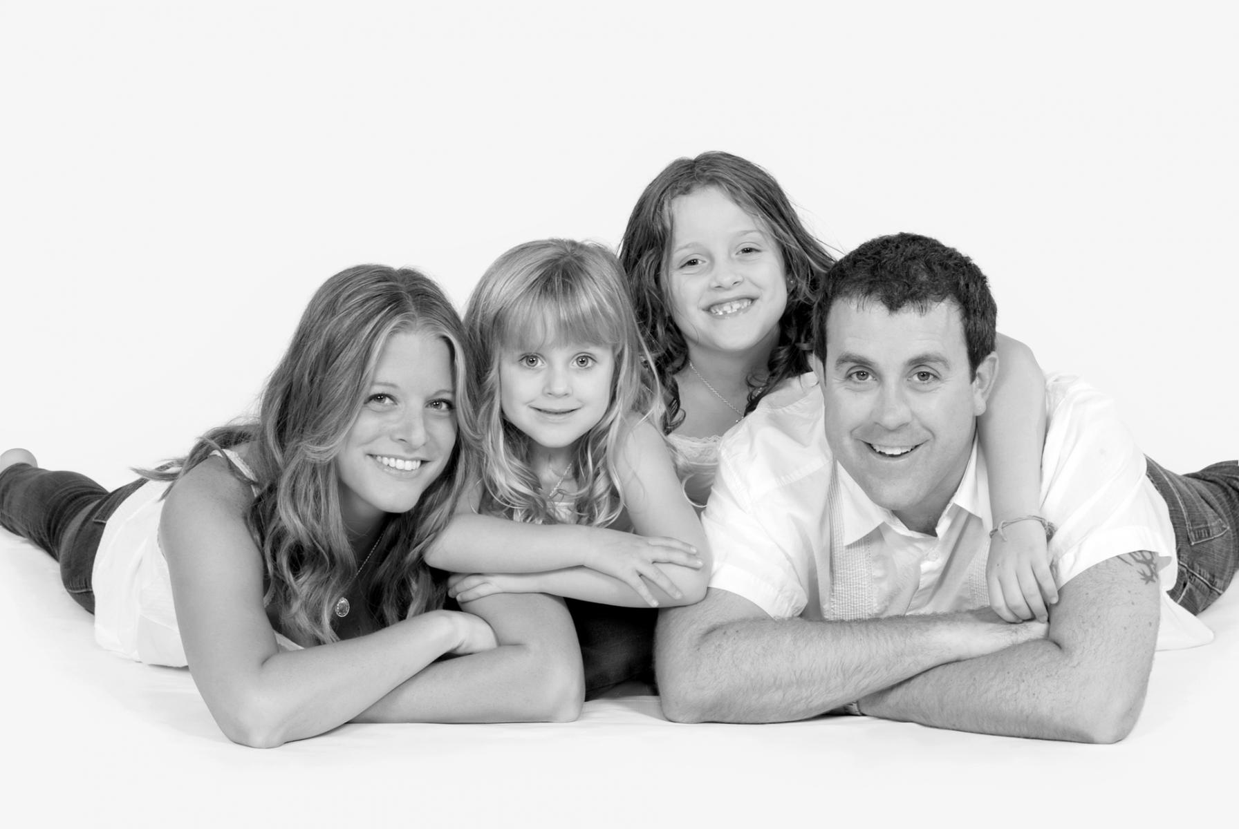 Spontaneous, playful portrait of a family photographed on high key, white background, by Robertsons' Warehouse Photography, Wichita, KS